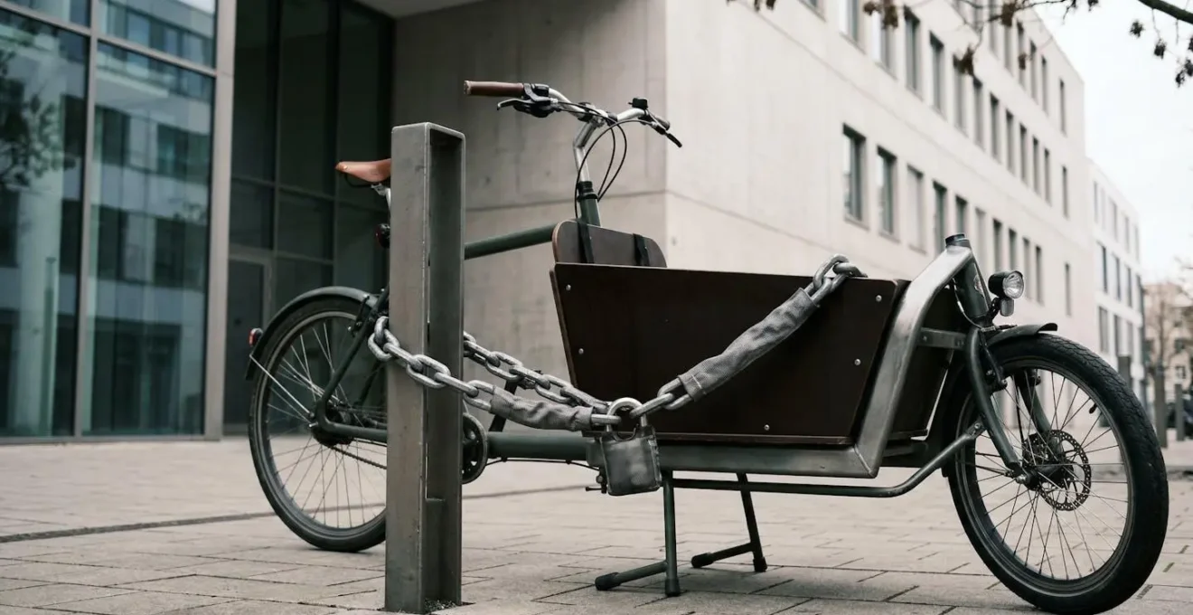 Vélo cargo sécurisé avec chaîne antivol professionnelle attaché à un point fixe en milieu urbain