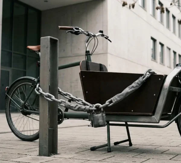 Vélo cargo sécurisé avec chaîne antivol professionnelle attaché à un point fixe en milieu urbain