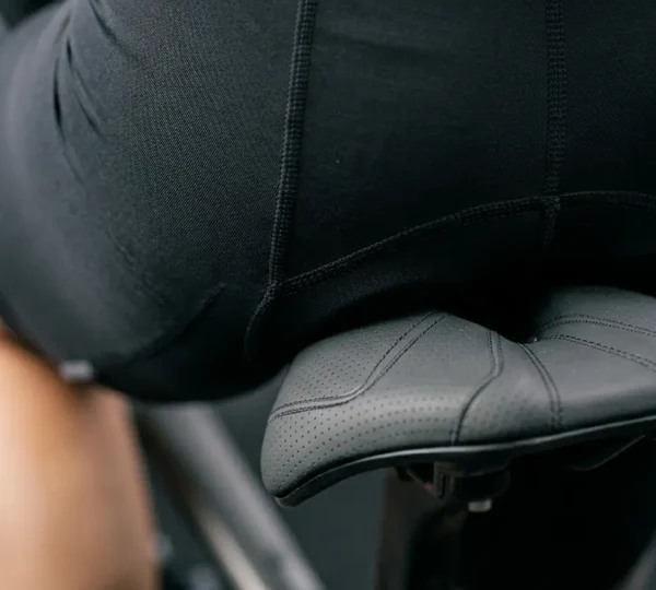 Gros plan photographique sur la zone de contact entre le bassin et une selle de vélo, montrant la géométrie et la largeur adaptée pour un confort optimal