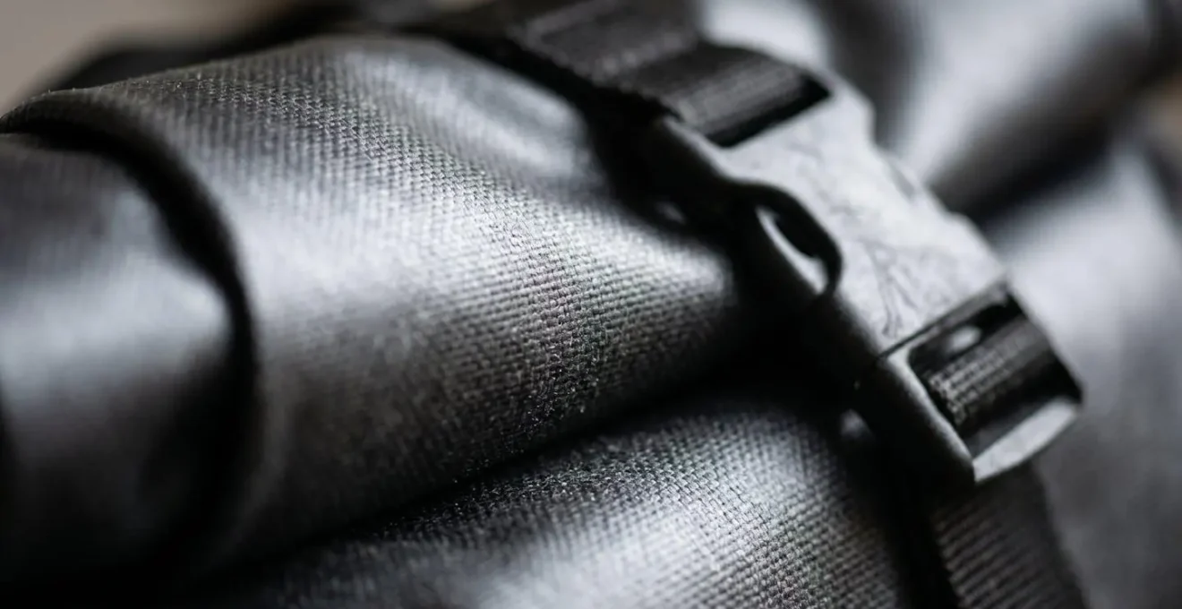 Détail macro d'une fermeture roll-top de sacoche étanche montrant la texture du matériau et le système d'enroulement